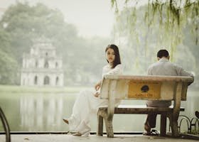 A couple sitting on a bench near Hanoi's iconic Turtle Tower, seemingly deep in thought.
