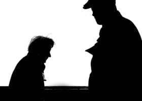 High contrast silhouette photo capturing two adults conversing against a white background.